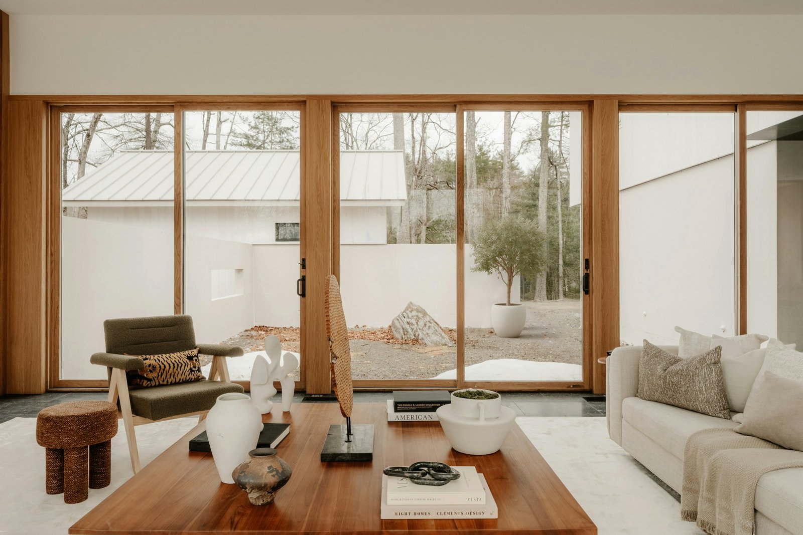 A sunlit interior with natural wood, linen upholstery and a quiet courtyard